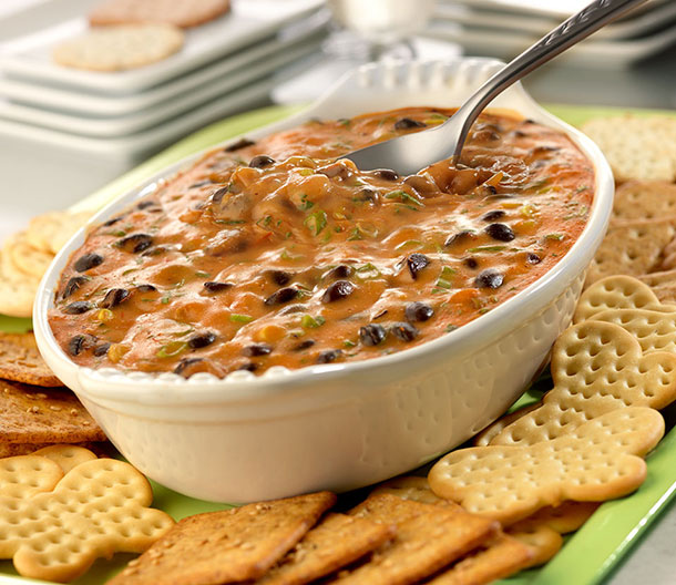 An image of prepared Queso-Style Bean Dip made with Campbell's® Condensed Cheddar Cheese Soup, Pace® Picante Sauce, cilantro, green onion, black beans and Pepperidge Farm® crackers.